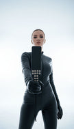 Жена в латексов костюм държи кожен bdsm падъл с метални капси