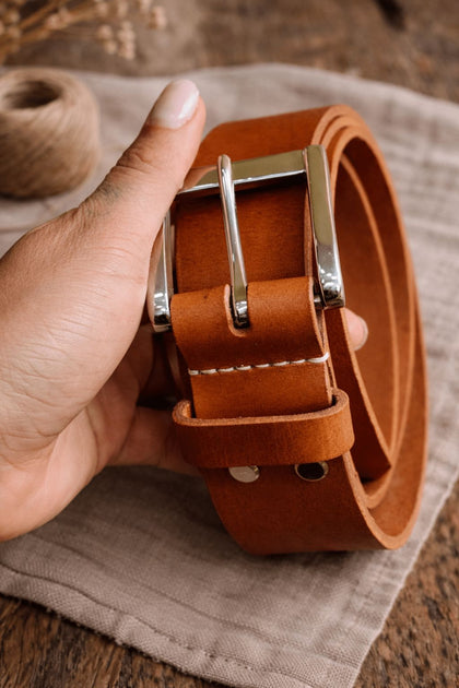 Кожен колан Sova с метална катарама, държан в ръка